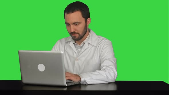 Concentrated Male Doctor Using Laptop at Medical Office on a Green Screen, Chroma Key