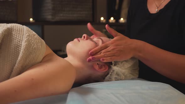 A Female Masseur Gives a Wellness Facial Massage to a Client