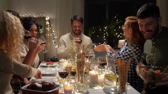 Happy Friends Drinking Red Wine at Christmas Party