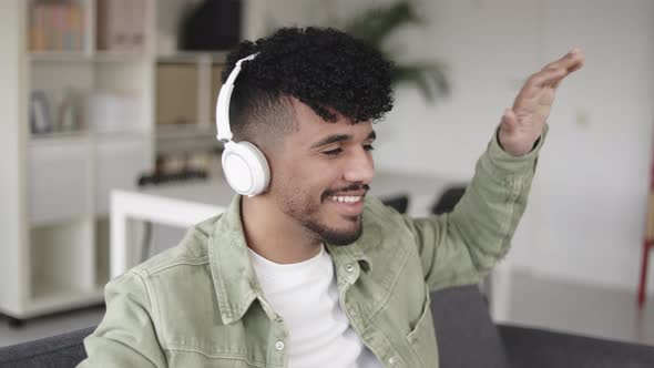Young Latino Man Dancing While Listening Music with Headphones at Home alt