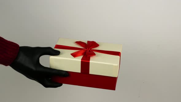 A man gives a woman a gift box in black COVID 19 gloves. Christmas shopping during the quarantine