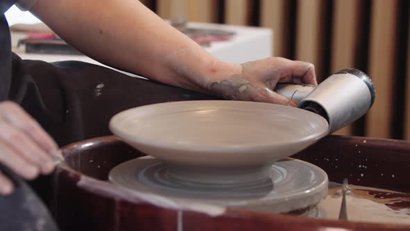 A Woman Heating a Clay Plate on the Wheel Using Hairdryer