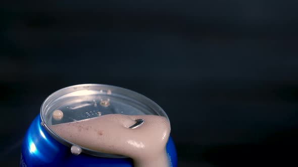 Opening a Shaken Blue Can of Beer Cola From Which a Frothy Drink is Poured