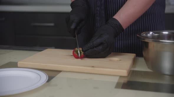 Confectionery  Pastry Chef Cuts Strawberries for Cake Decorating in Halves