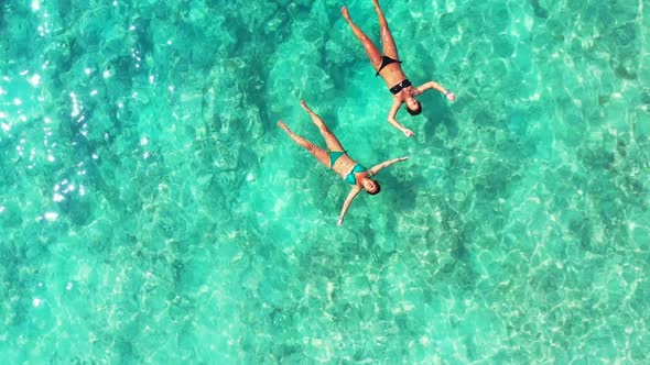 Girls happy and smiling on relaxing lagoon beach wildlife by shallow lagoon with white sandy backgro