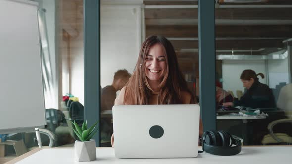 Young Attractive Woman in a Sweatshirt Sit on Chair Celebrate Good News Read Online on Laptop Low