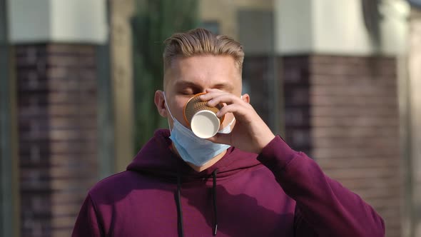 Portrait of Young Man Lowers a Medical Mask and Drinks Coffee While Enjoying an Aromatic Drink