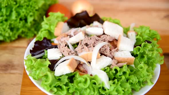 Closeup to tuna salad in the white dish on wood plate