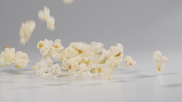 Fresh popcorn falling onto a white surface in slow motion