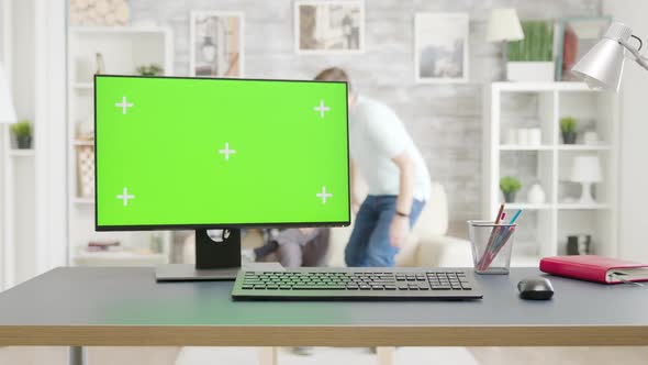 PC with Isolated Green Screen Mock-up on the Table in Bright Living Room