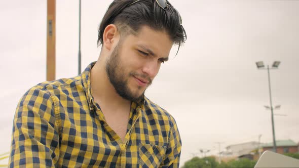 Handsome man siting on stairs using laptop outdoors