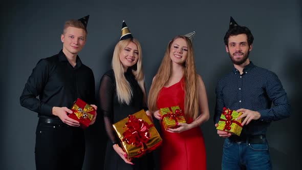 Two Attractive Guys and Two Beautiful Girls Pose with Festive Gift Boxes