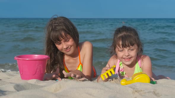 Kids on the beach play with sand. alt