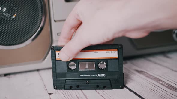 Female Hand Rotates an Old Music Audio Cassette on a Table Near a Tape Recorder