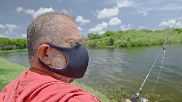 Slow Motion of Elderly Man Wearing Face Mask While Fishing on a Lake