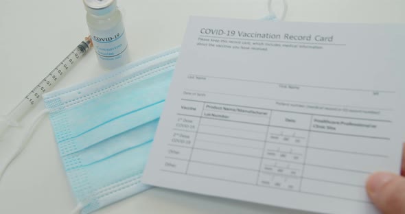 Medical Mask and COVID19 Vaccine Doctor Hand Put Vaccination Record Card