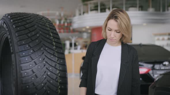 A Woman in a Car Dealership of an Official Dealer Chooses Tires