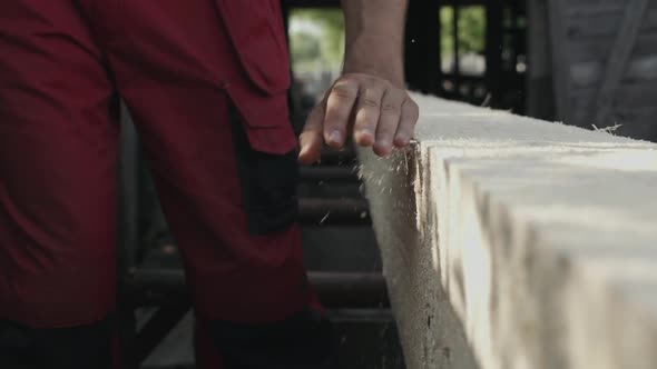 Hand Sweeps Sawdust From a Wooden Beam