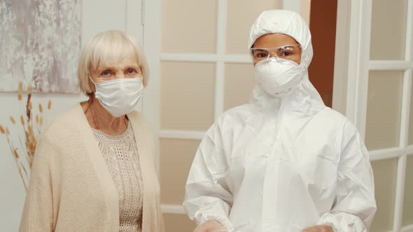 Portrait of Doctor in Protective Suit and Old Woman in Mask