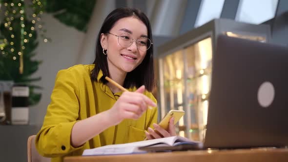 Portrait of Positive Asian Female in Classic Eyewear Smiling at Camera While Spending Day for