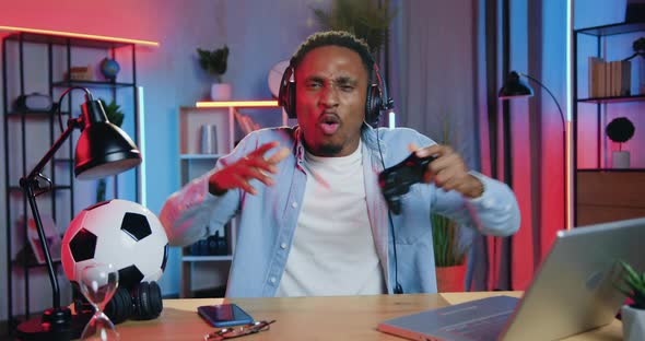 Black-Skinned Guy in Headphones Sitting in front of Camera and Playing Video Games