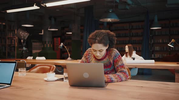 Mixed Race Female Studying Remotely Using Laptop at Modern Library