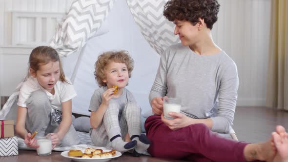 Happy Family Eating Cookies with Milk beside Teepee in Kids Room