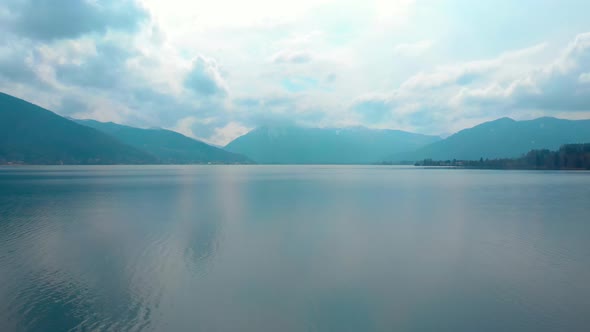 Flying forwards over the Tegernsee while ascending, Wallberg covered in clouds.