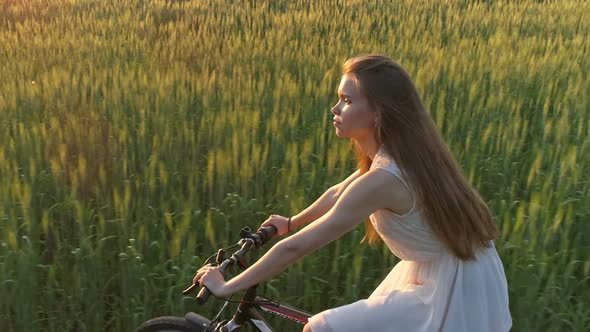 Cute Young Girl on Bicycle in Green Field