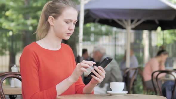 Young Woman Using Smartphone Sitting in Cafe Terrace