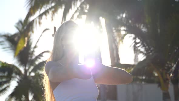 Closeup of backlit side shot of backlit mature woman with hands in prayer, lowering them from above