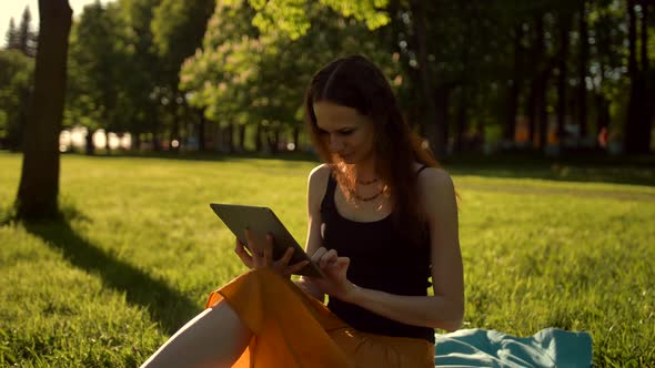 Young Lady Browsing Her Tablet in the Park.