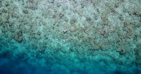 Wide angle overhead clean view of a white sand paradise beach and blue sea background in vibrant 4K