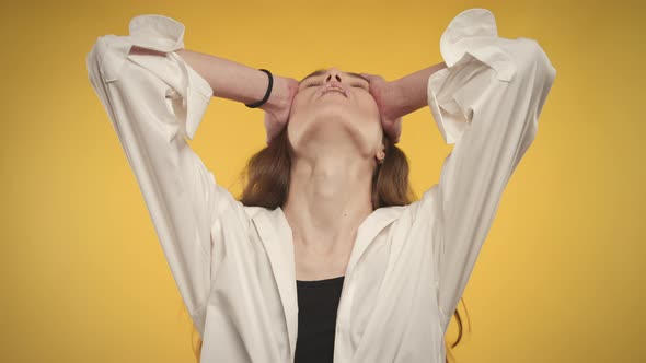 Young Adult Caucasian Woman is Feeling Anxious on a Bright Yellow Background in Studio