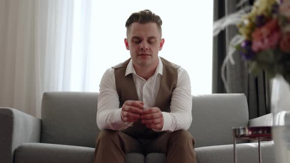 Man in Vest is Sitting on Sofa and Depressed Completely Upset He Covers His Face with His Hands