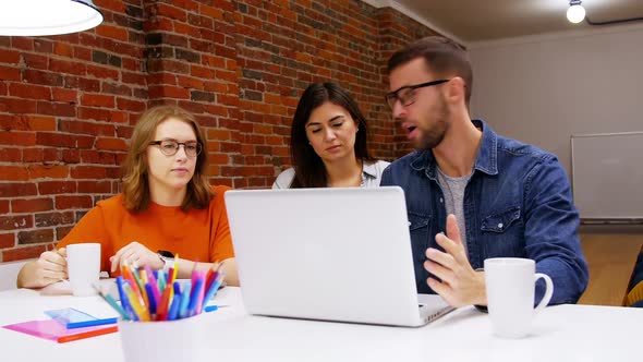 Group of executives discussing over laptop in the conference room