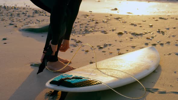 Side view of mid-adult caucasian male surfer tying surfboard leash at the beach 4k