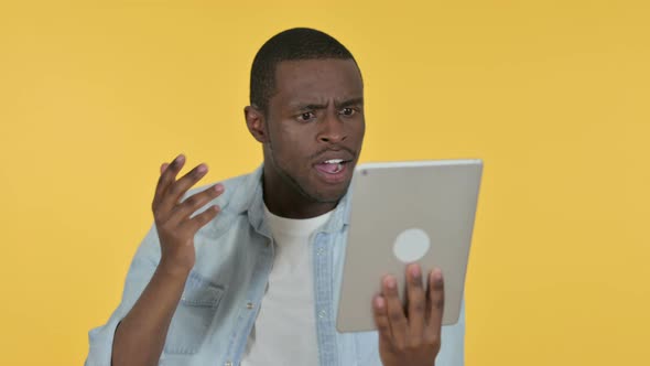 Young African Man Reacting To Loss on Tablet, Yellow Background 