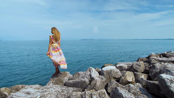 Girl in a Beautiful Dress on Stones Looking at the Ocean