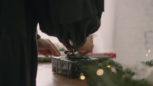 Closeup of the Hands Packing and Putting a Gift with Garlands for Christmas