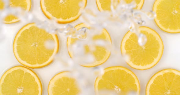 Super Slow Motion Shot of Splashing Water To Many Orange Slices View From Above.