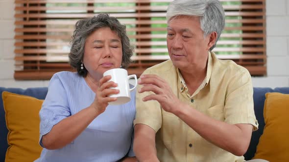 Asian senior couple elderly taking pills, drinking water in the living room at home.