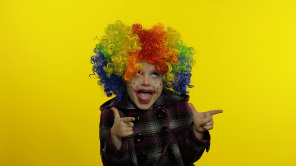Little Child Girl Clown in Colorful Wig Making Silly Faces, Having Fun, Smiling, Dancing. Halloween