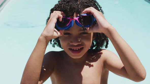 Portrait of happy biracial boy looking at camera in swimming pool