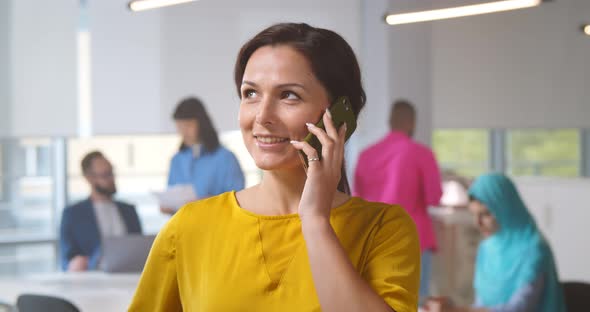 Portrait of Charming Young Lady Having Phone Conversation Standing at Office