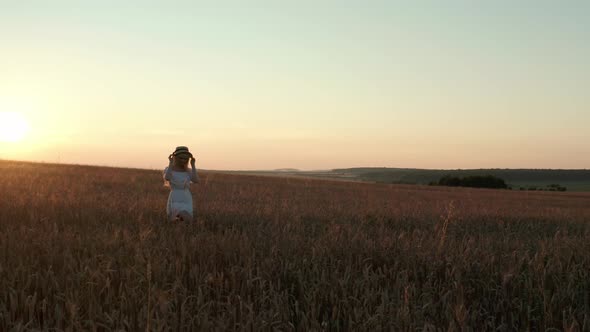 Aerial Drone View A Woman Happily Walking Through a Field Touching with Hand Wheat Ears and Sunlight