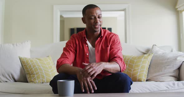 Happy biracial man sitting on sofa and having video call