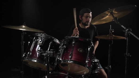 Young Man Playing on Drum Kit Over Black Background Slow Motion