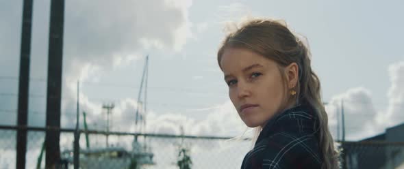 Young blonde woman looks into the camera while wind blows her hair