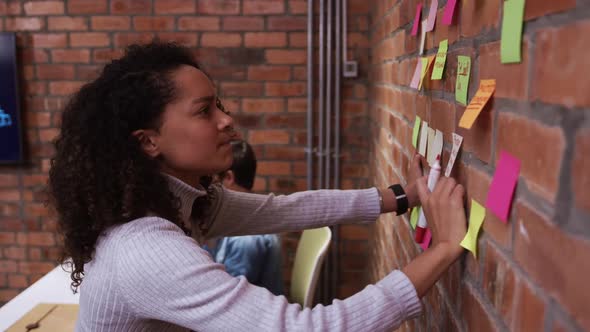 Creative businesswoman writing on sticky notes in modern office